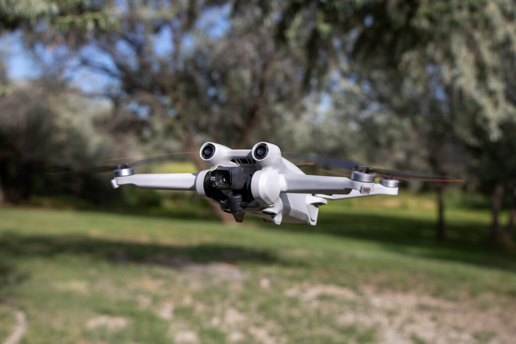 Gros plan sur un drone avec capteurs de caméra et hélices en vol, avec la nature en arrière-plan – DJI Mini 3 Pro, drone aérien