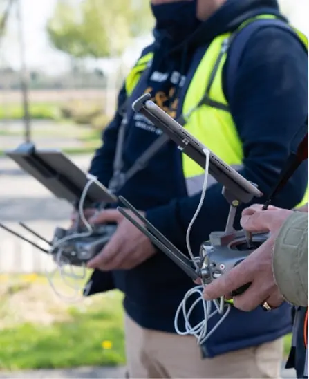 Deux télépilotes tenant des radiocommandes de drones avec tablettes intégrées, en extérieur durant une session de formation