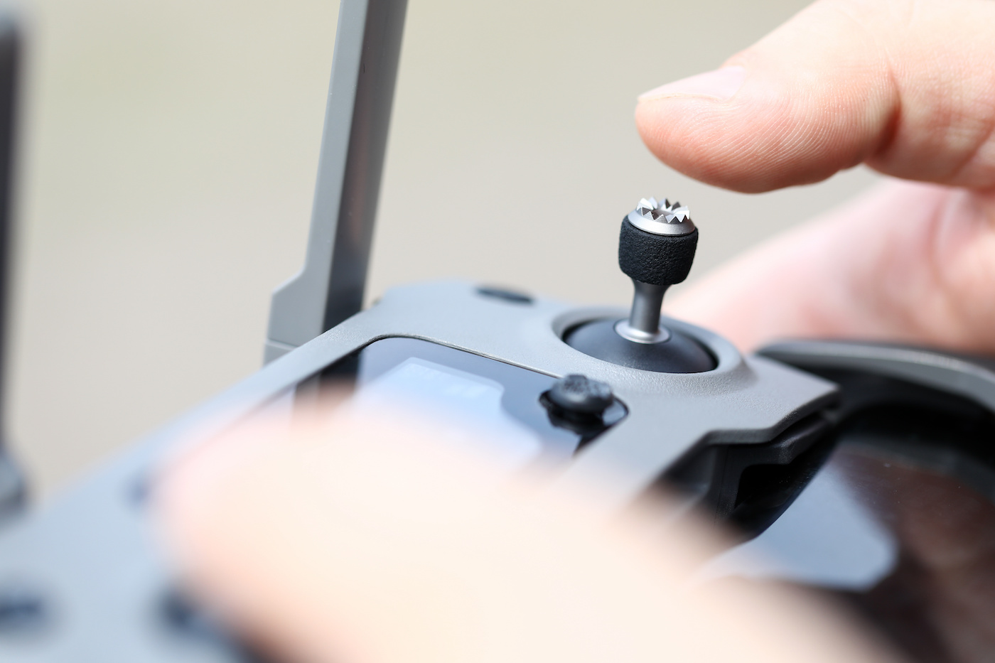 Main masculine tenant la télécommande d’un drone moderne et le pilotant avec un joystick en gros plan.